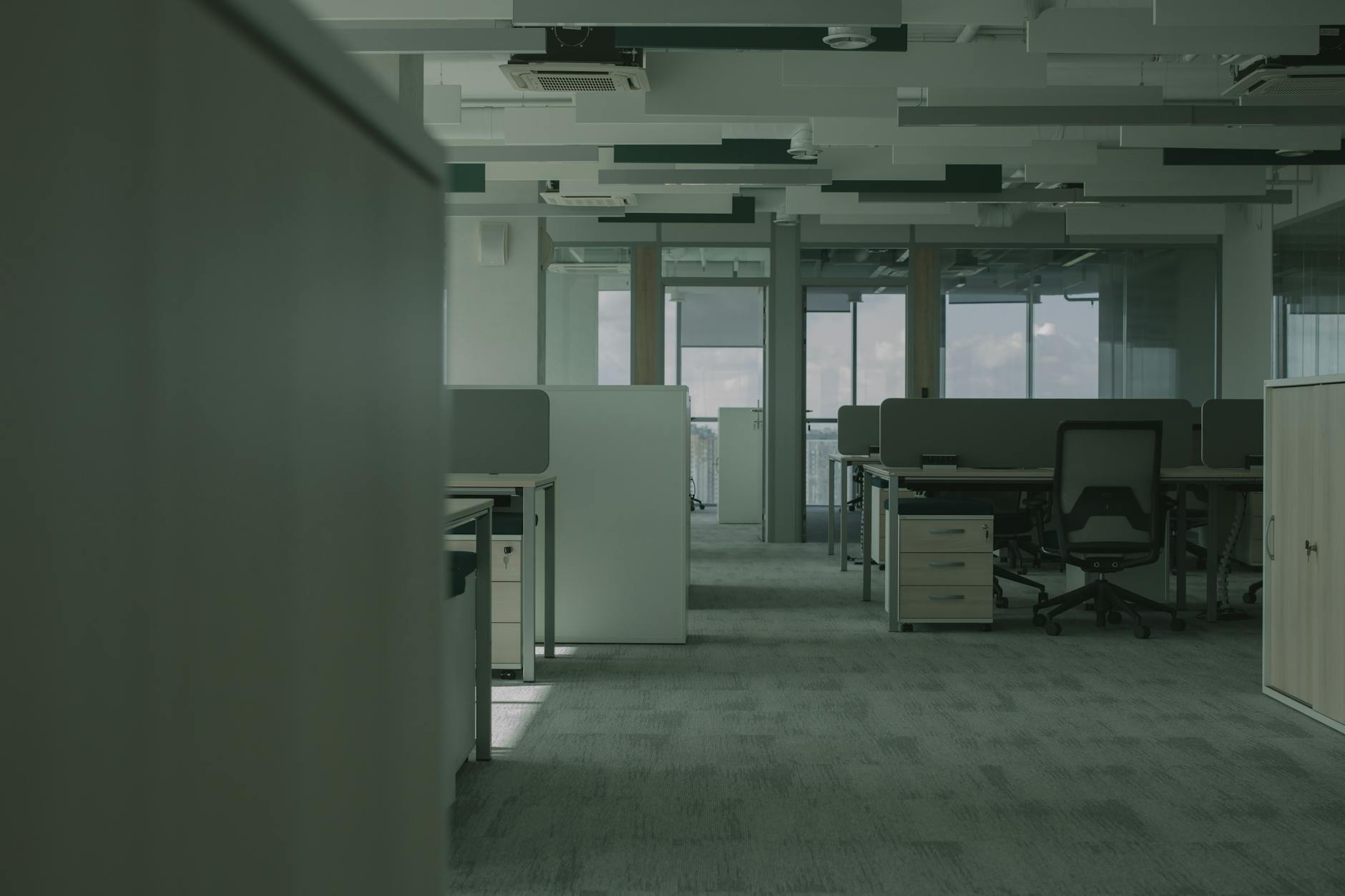 Empty modern office space with vacant desks and chairs showing reduced workplace occupancy