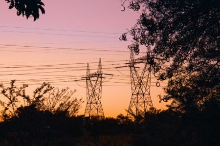 Electrical transmission lines silhouetted against sunset sky