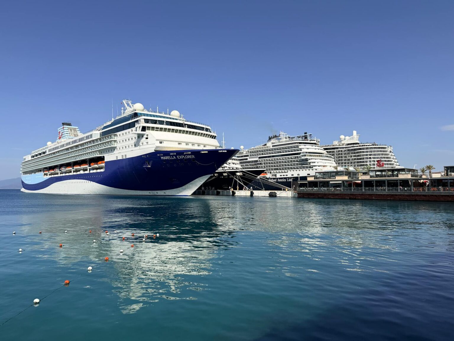 Large cruise ship sailing in Mediterranean waters with coastal mountains in background