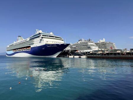 Large cruise ship sailing in Mediterranean waters with coastal mountains in background
