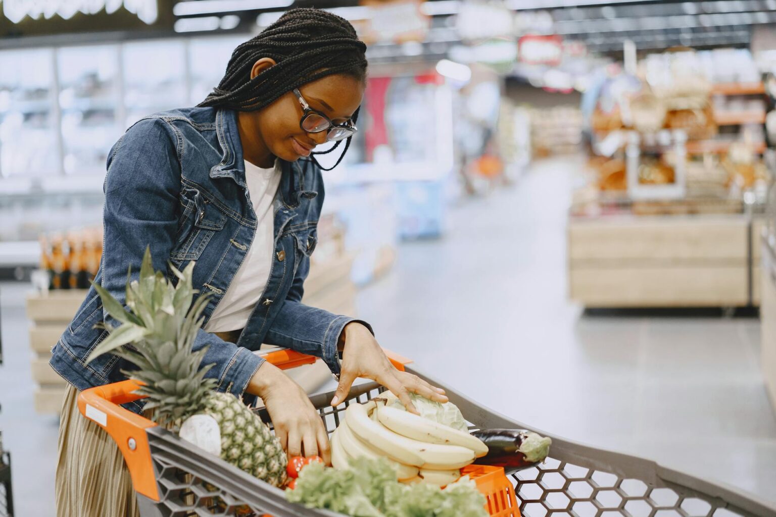Shopping cart filled with groceries in supermarket aisle