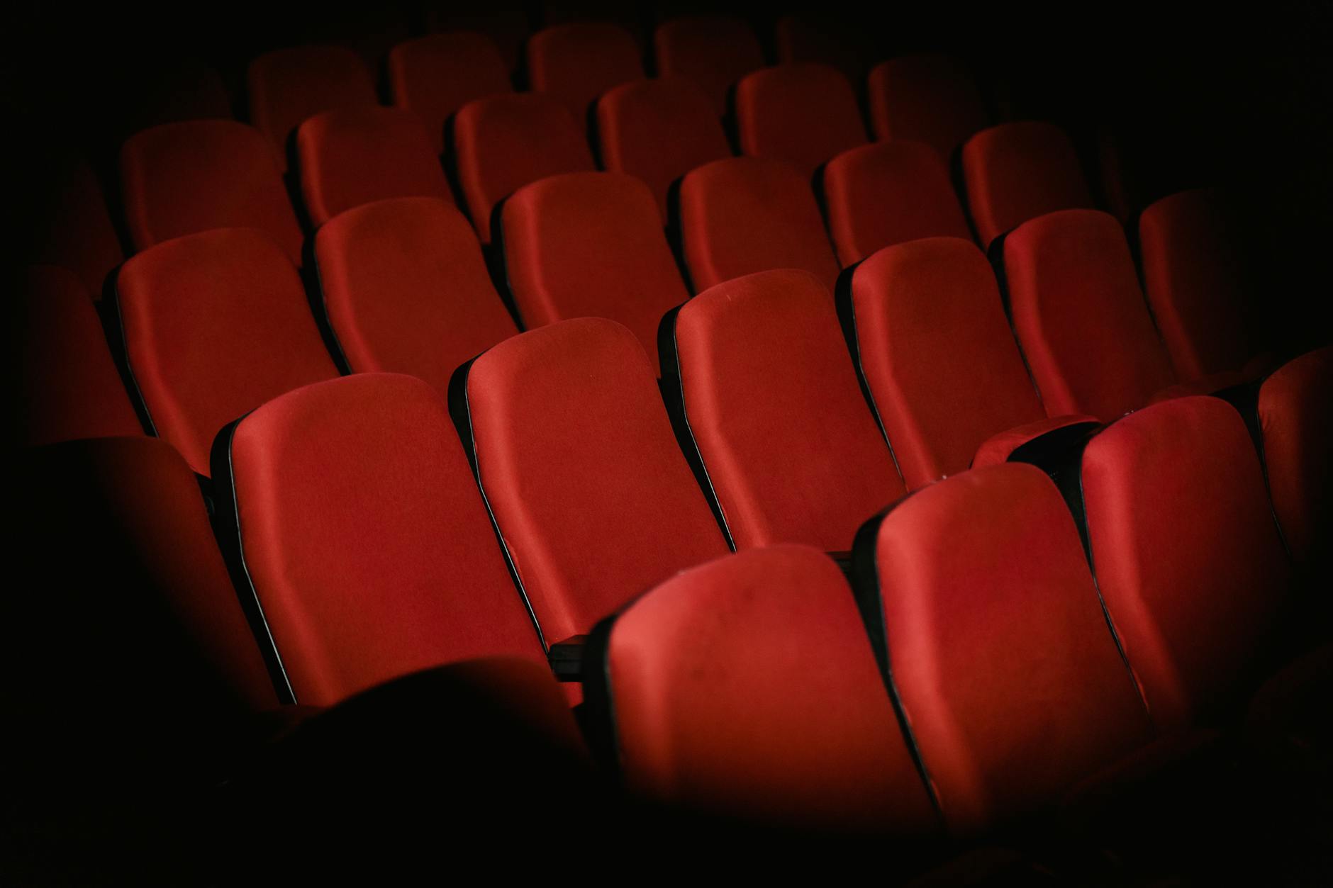 Empty movie theater with red seats and large screen, representing venues being converted for corporate events