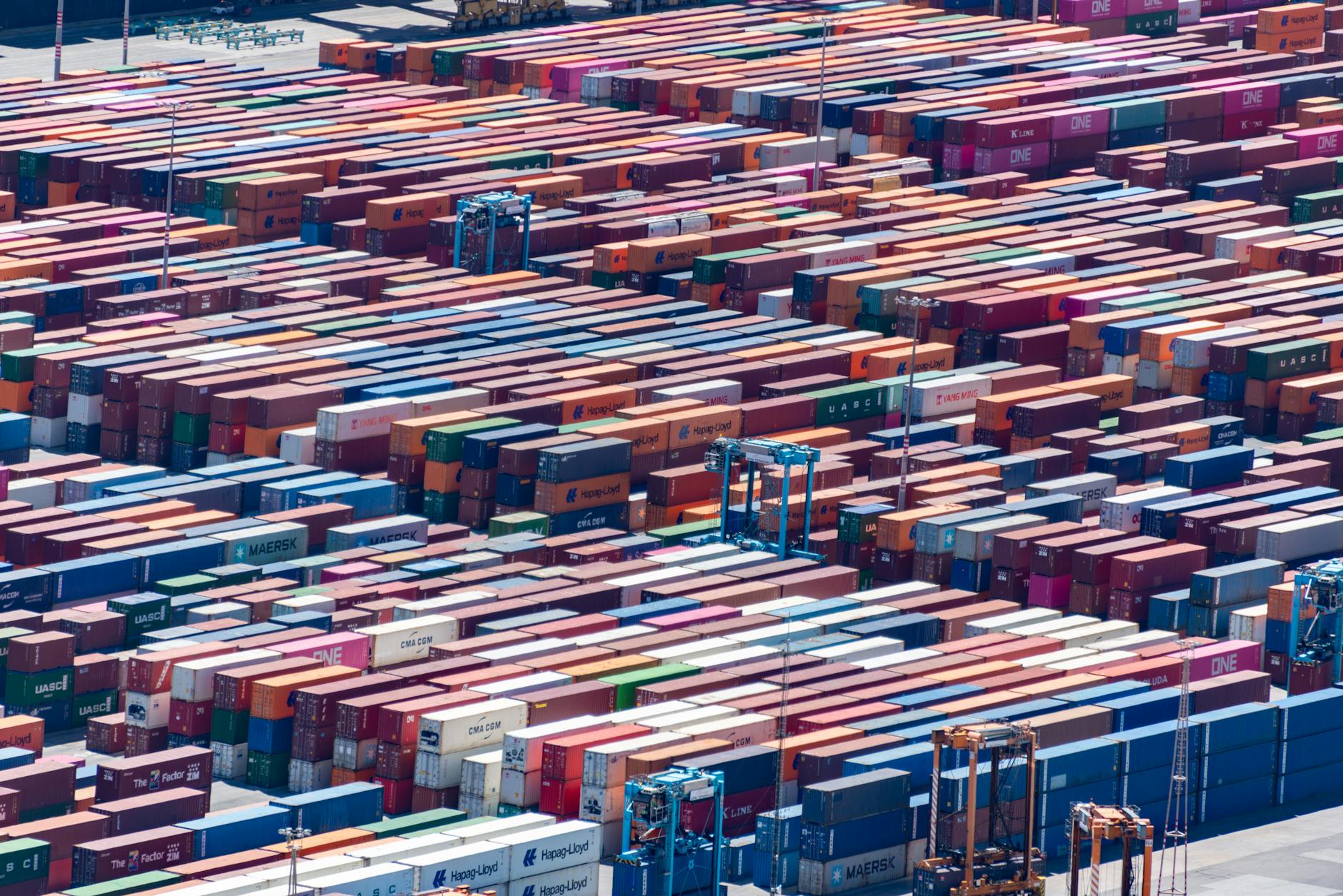 Aerial view of colorful shipping containers stacked at busy port terminal
