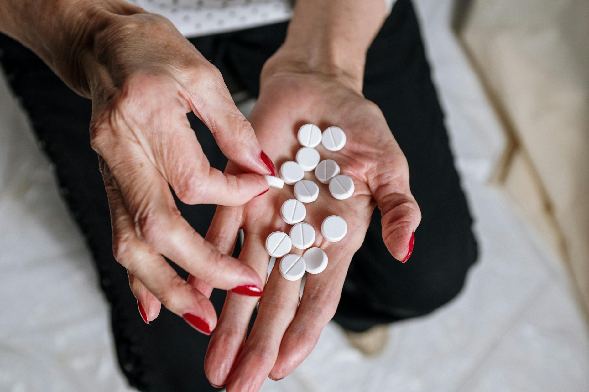 Senior woman holding prescription medication bottles at kitchen table