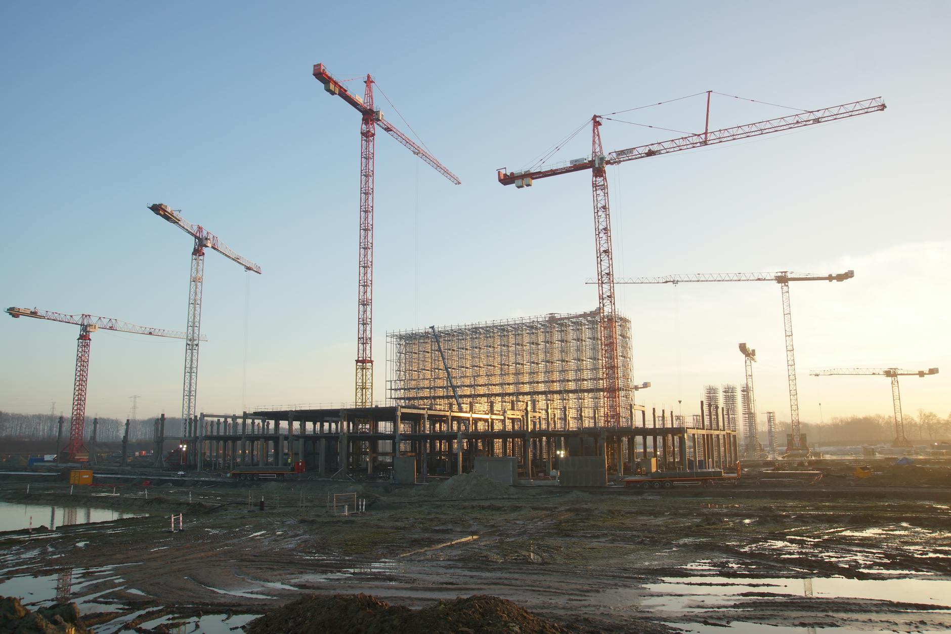 Construction site showing industrial building development with cranes and steel framework