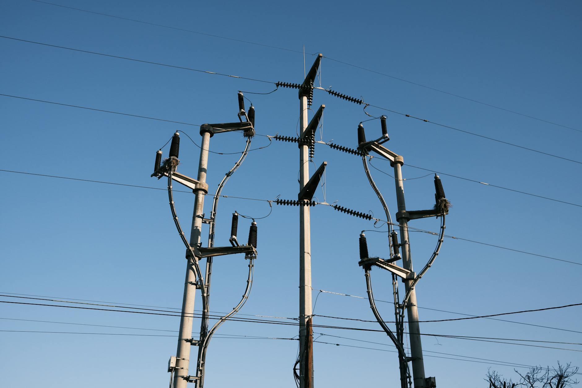 High voltage electrical transmission towers and power lines against blue sky
