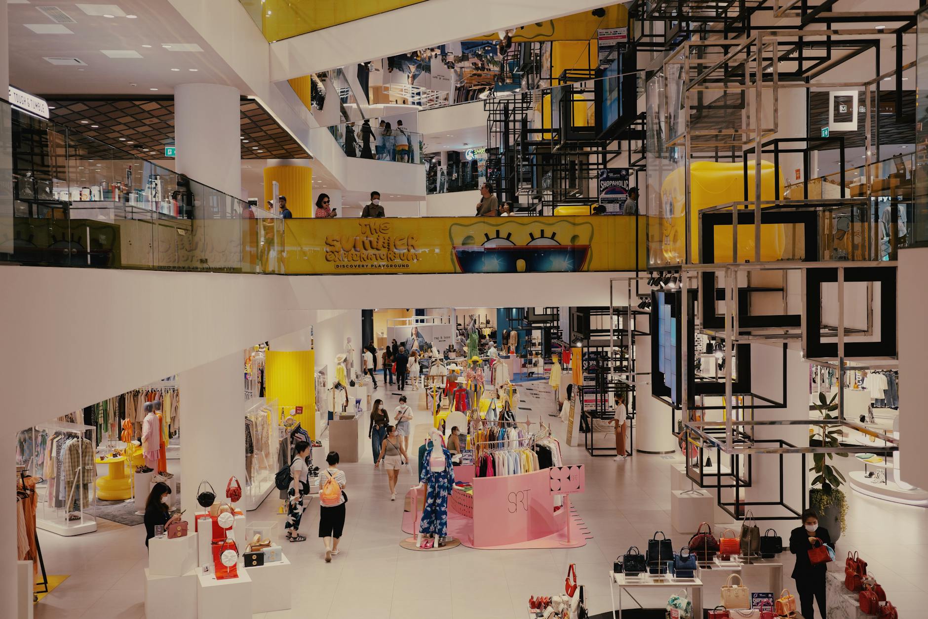 Modern shopping mall interior with fewer shoppers walking past retail stores