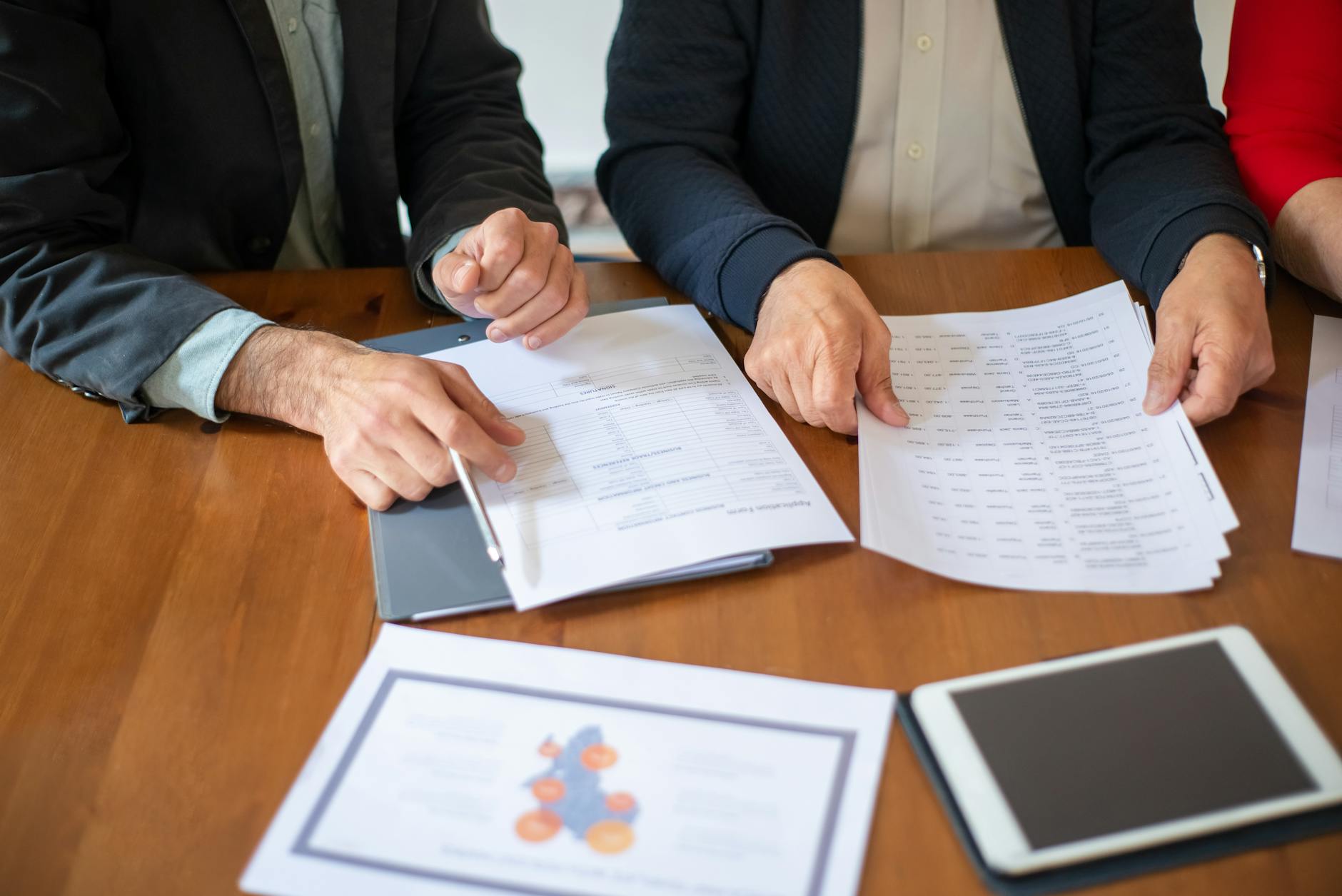 Business professionals reviewing investment documents and financial reports at conference table