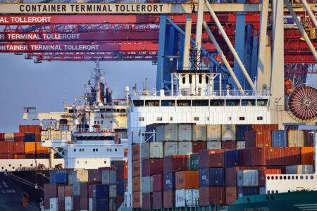 Large cargo shipping containers stacked at a commercial port representing import supply chains