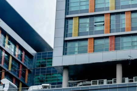 Major Tech Companies Reduce Office Space as Hybrid Work Becomes Permanent Modern office building exterior with glass windows reflecting empty floors