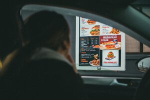 Major Fast Food Chains Eliminate Drive-Thru Windows to Cut Labor Costs Modern fast food restaurant exterior with parking area and pickup zones