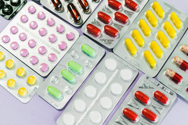 Medicaid Pharmacy Carve-Outs Squeeze Specialty Drug Access for Low-Income Patients Pharmacist reviewing prescription medications at a pharmacy counter