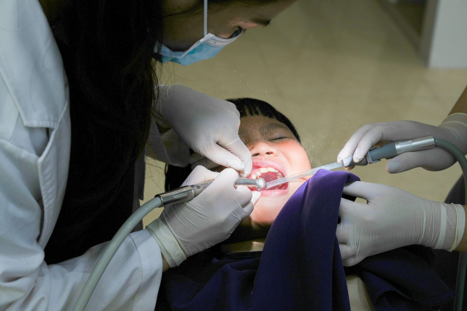 An older adult sitting in a dental chair during a checkup, representing seniors relying on Medicaid dental coverage