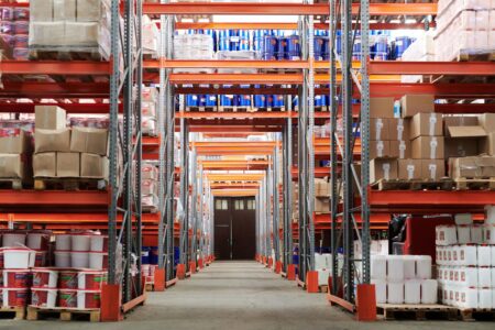Wide aisle inside a warehouse retail store stocked with bulk goods on metal shelving