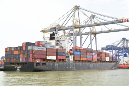 Large cargo containers stacked at a busy commercial port terminal