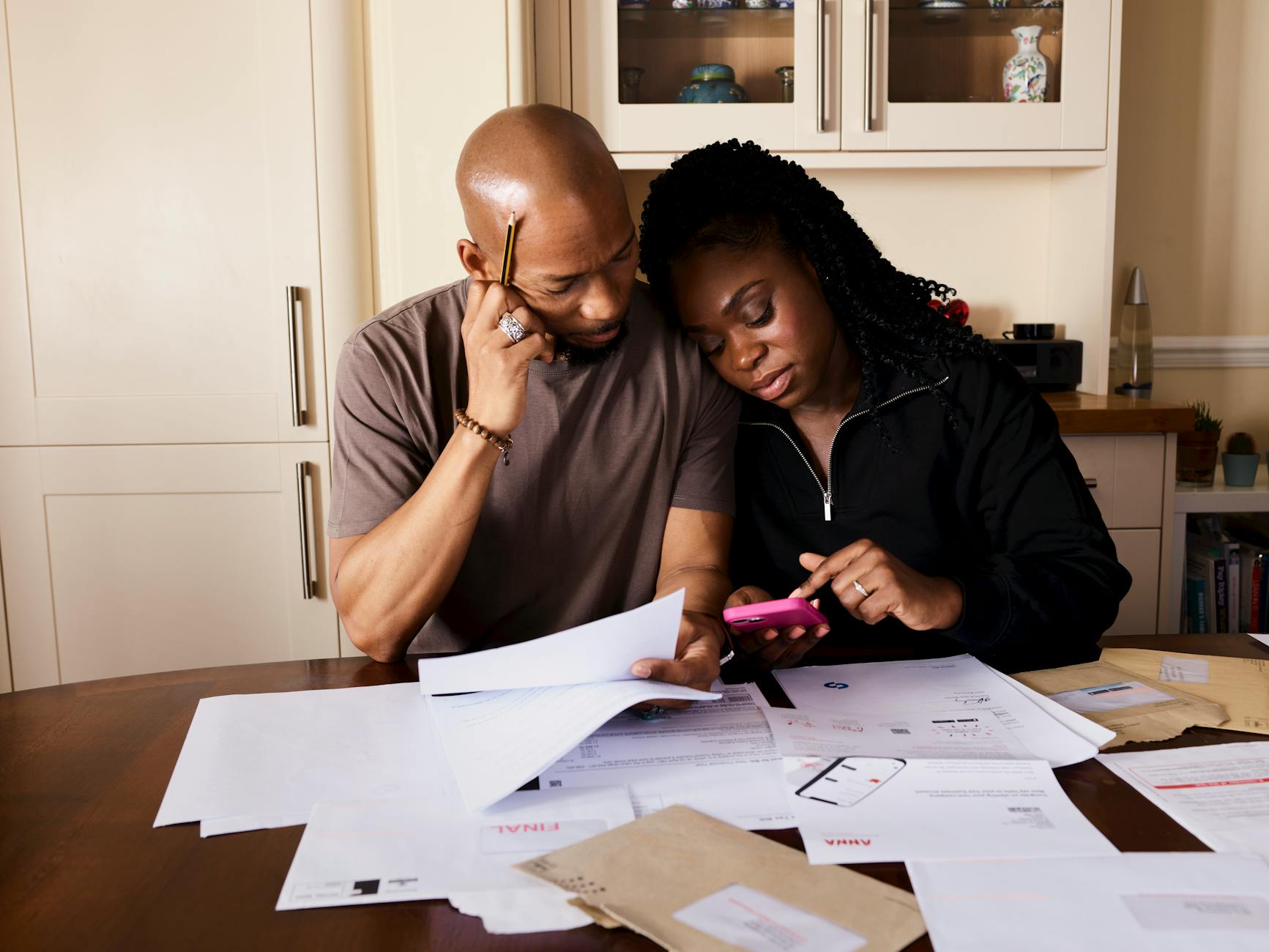 A woman reviewing household finances and bills at a kitchen table
