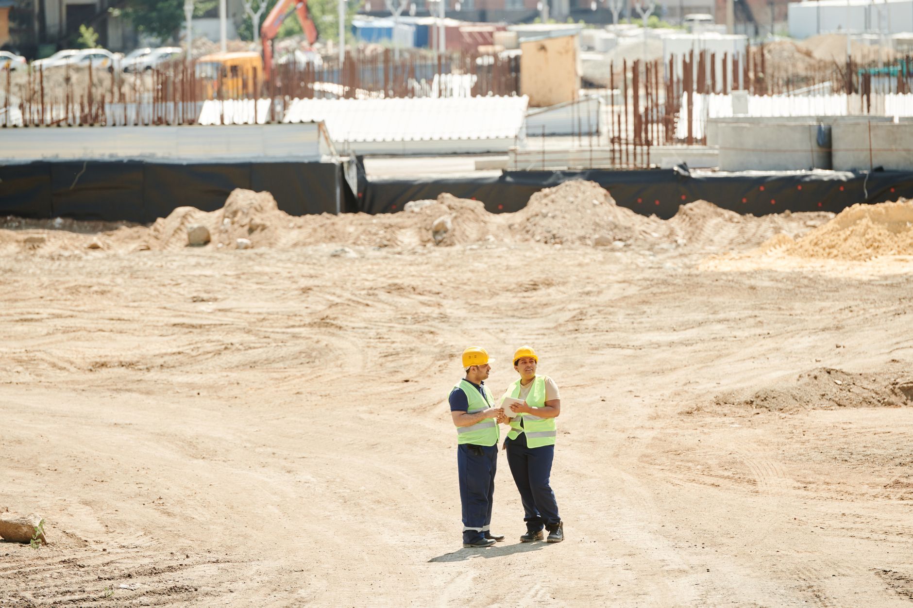 A worker in safety gear reviewing plans at a commercial solar installation site