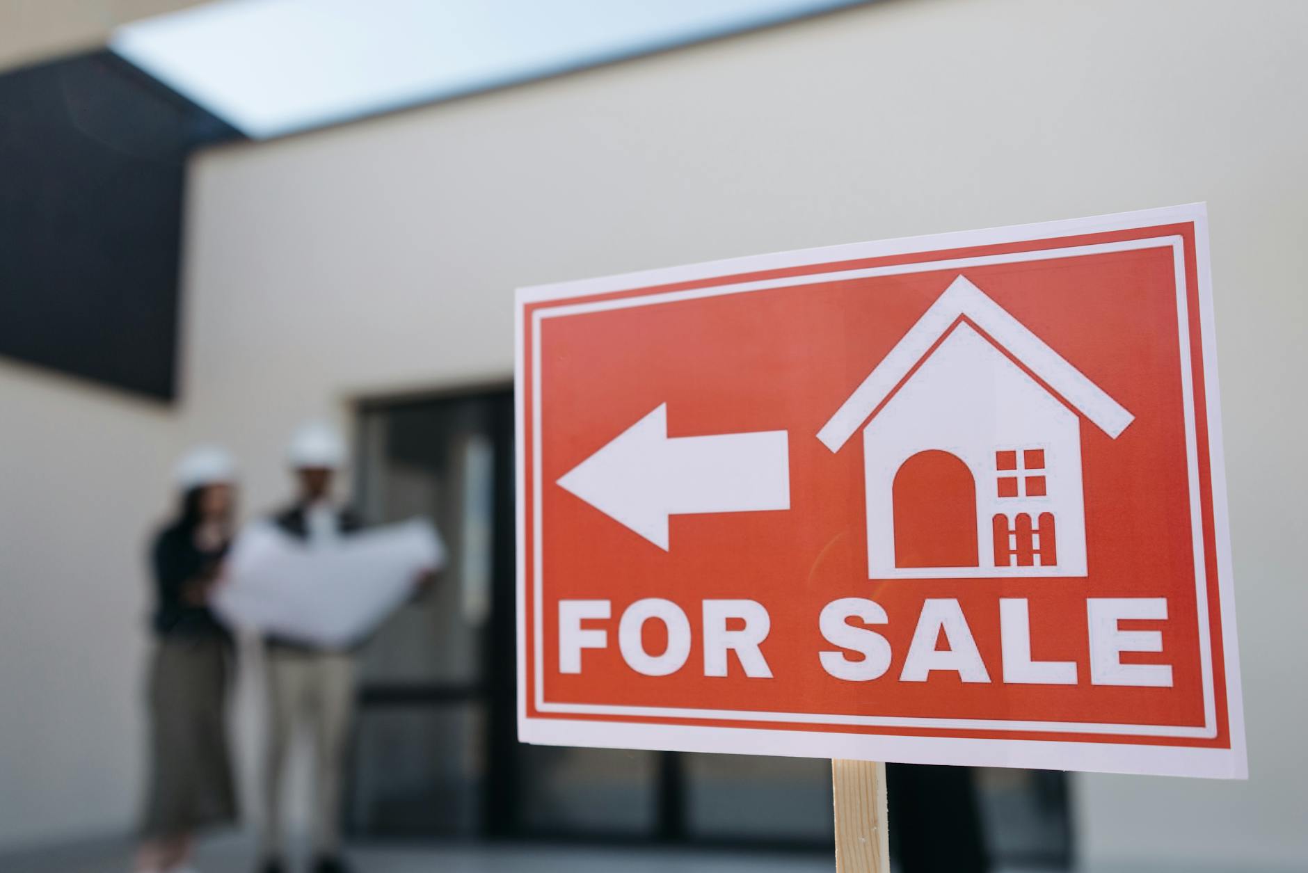 For sale sign in front of a residential home in a suburban neighborhood