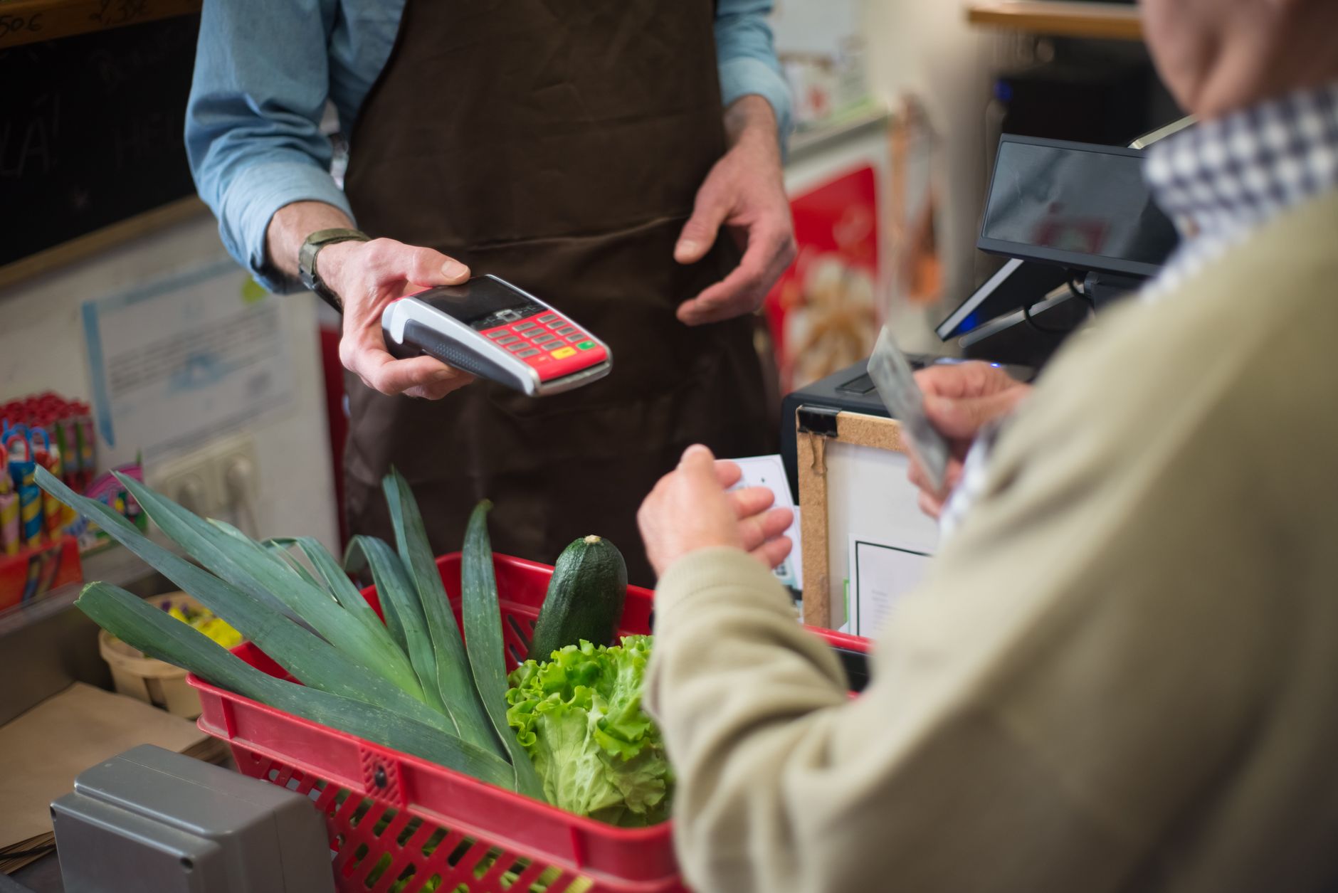 Shopper at supermarket checkout counter with groceries