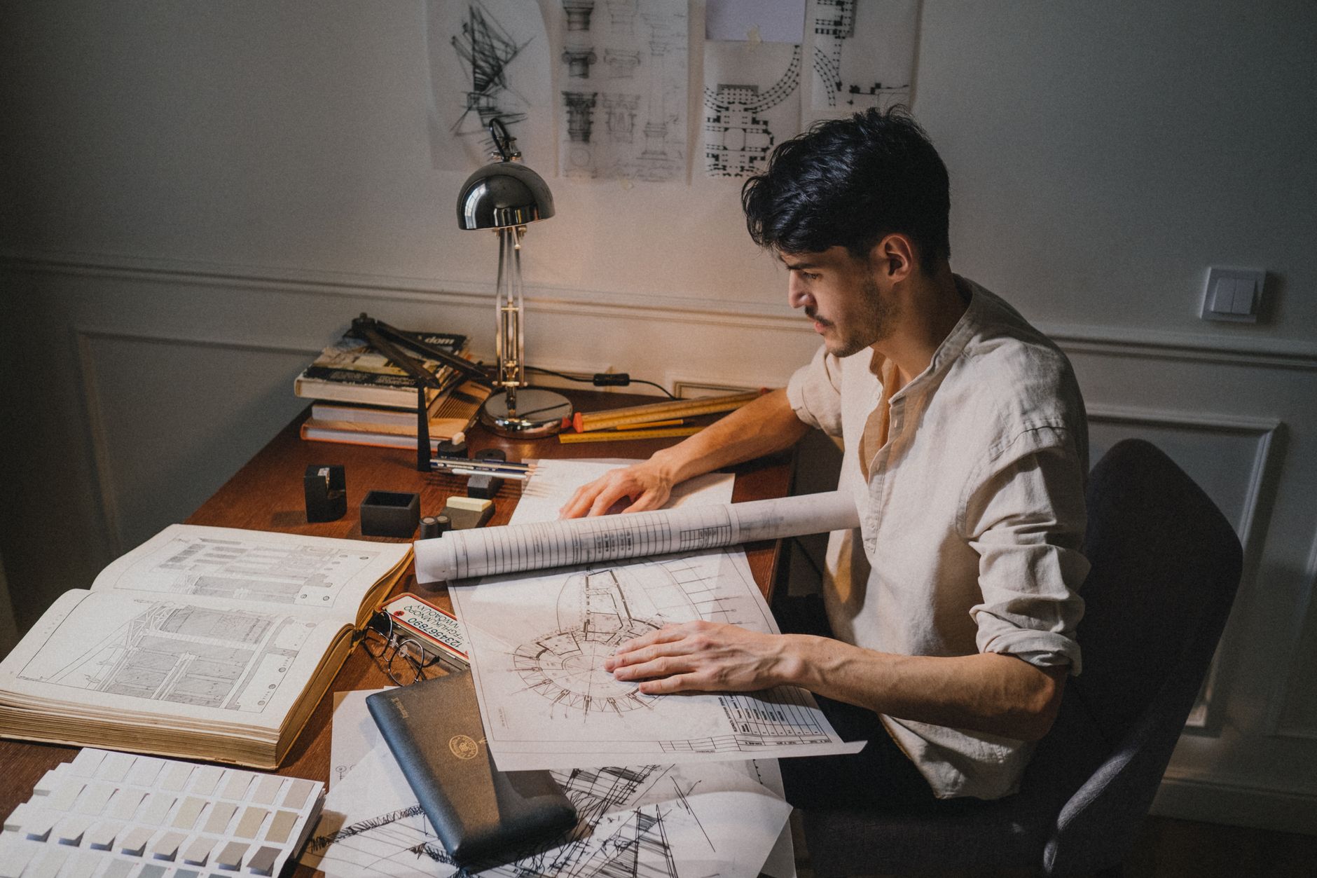 Architectural floor plan blueprints laid out on a desk with a pencil and ruler
