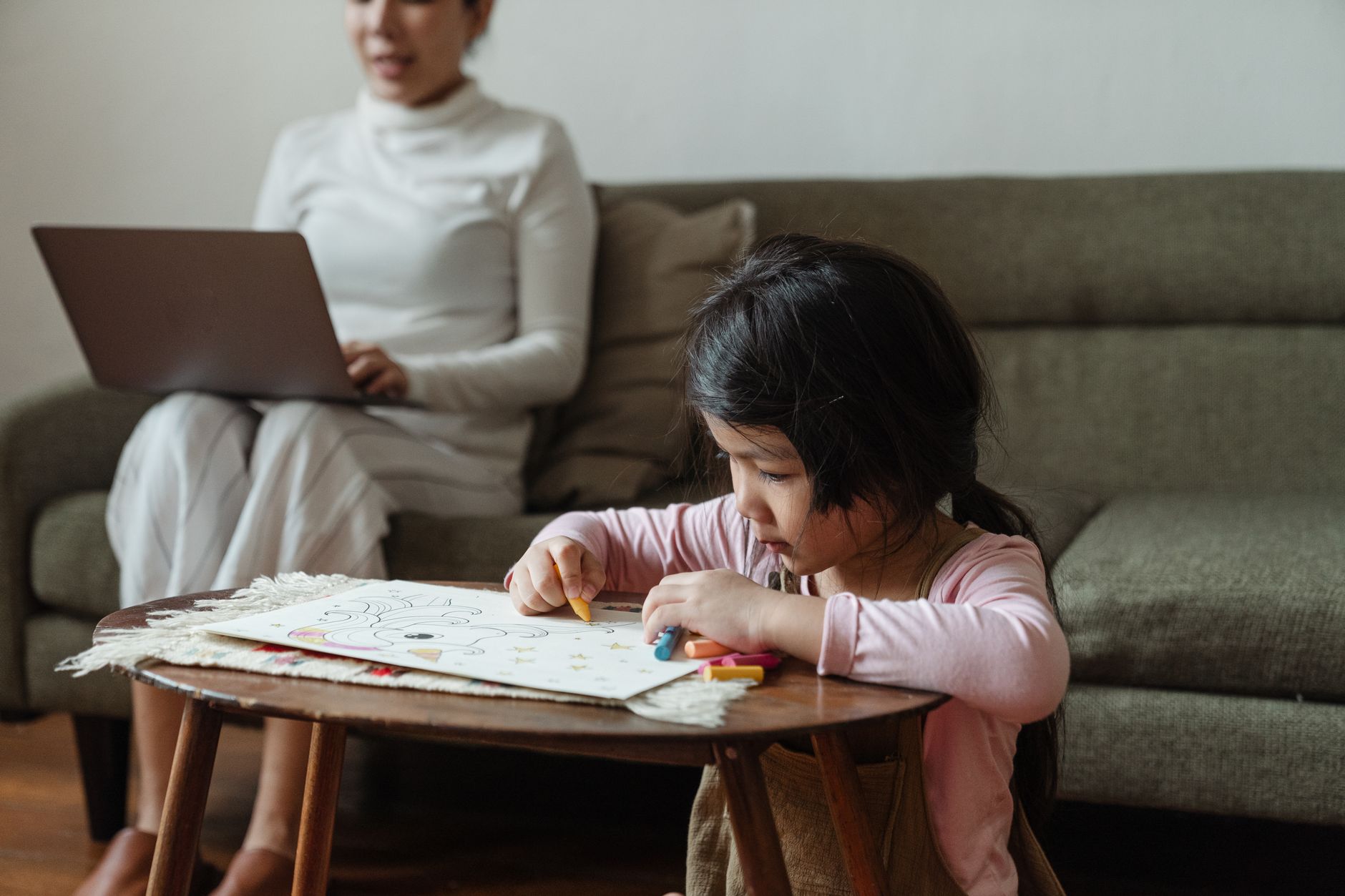 A mother working at a desk while managing family responsibilities at home
