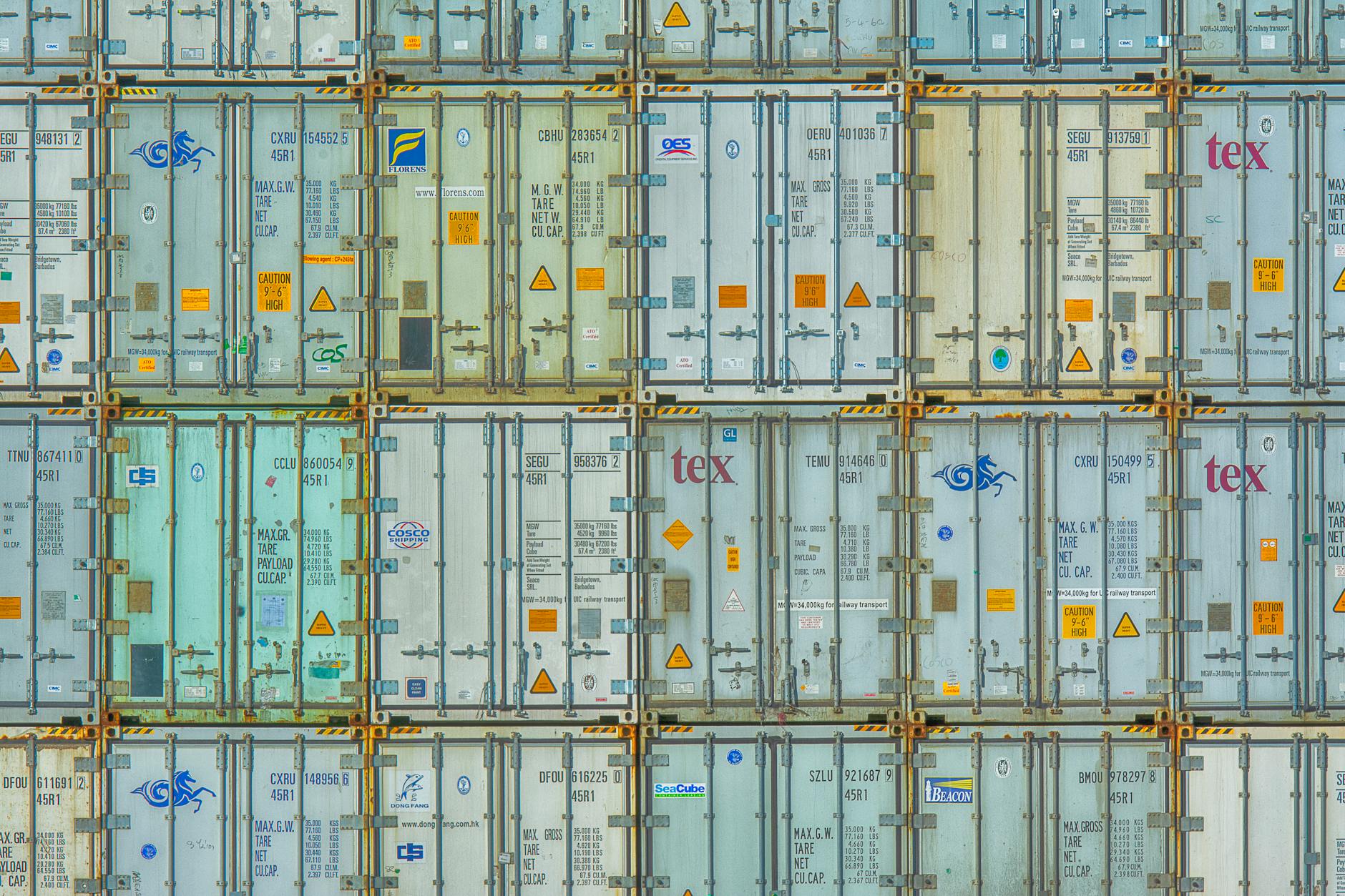 Stacked shipping containers at a warehouse facility representing import freight operations
