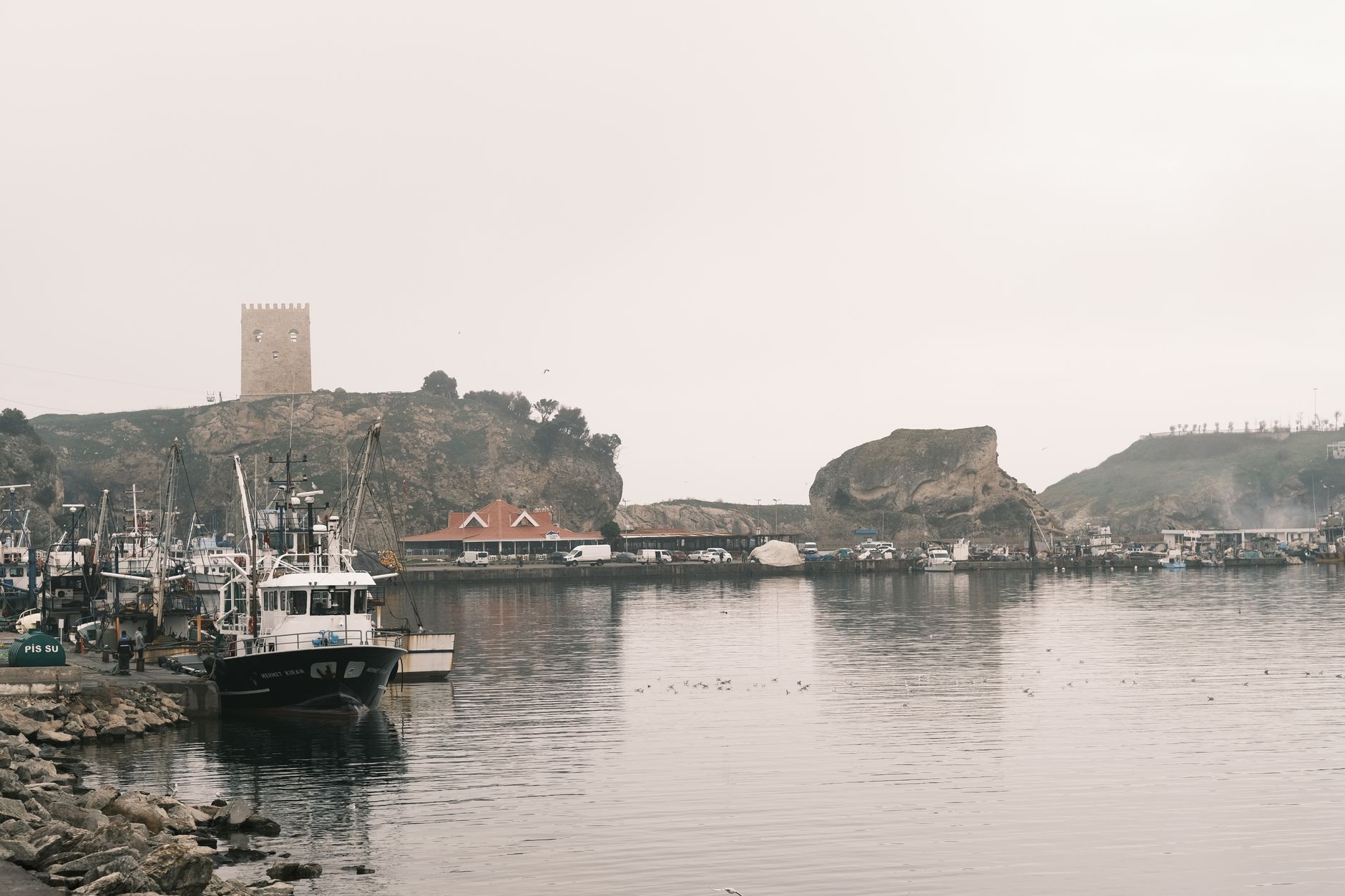 Fishing boats docked at a coastal harbor awaiting crew for summer season