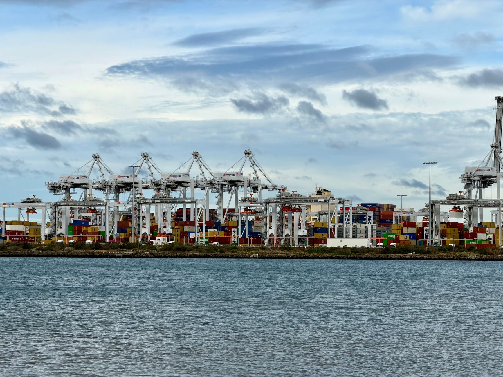 Large automated crane operating over a container terminal at dusk