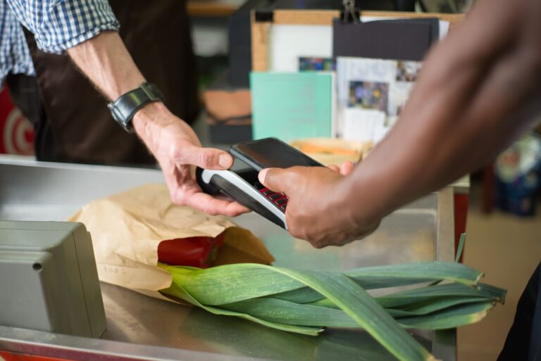 A shopper swiping a loyalty card at a grocery store checkout counter