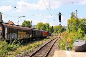 A long freight train carrying cargo containers across an open rail corridor