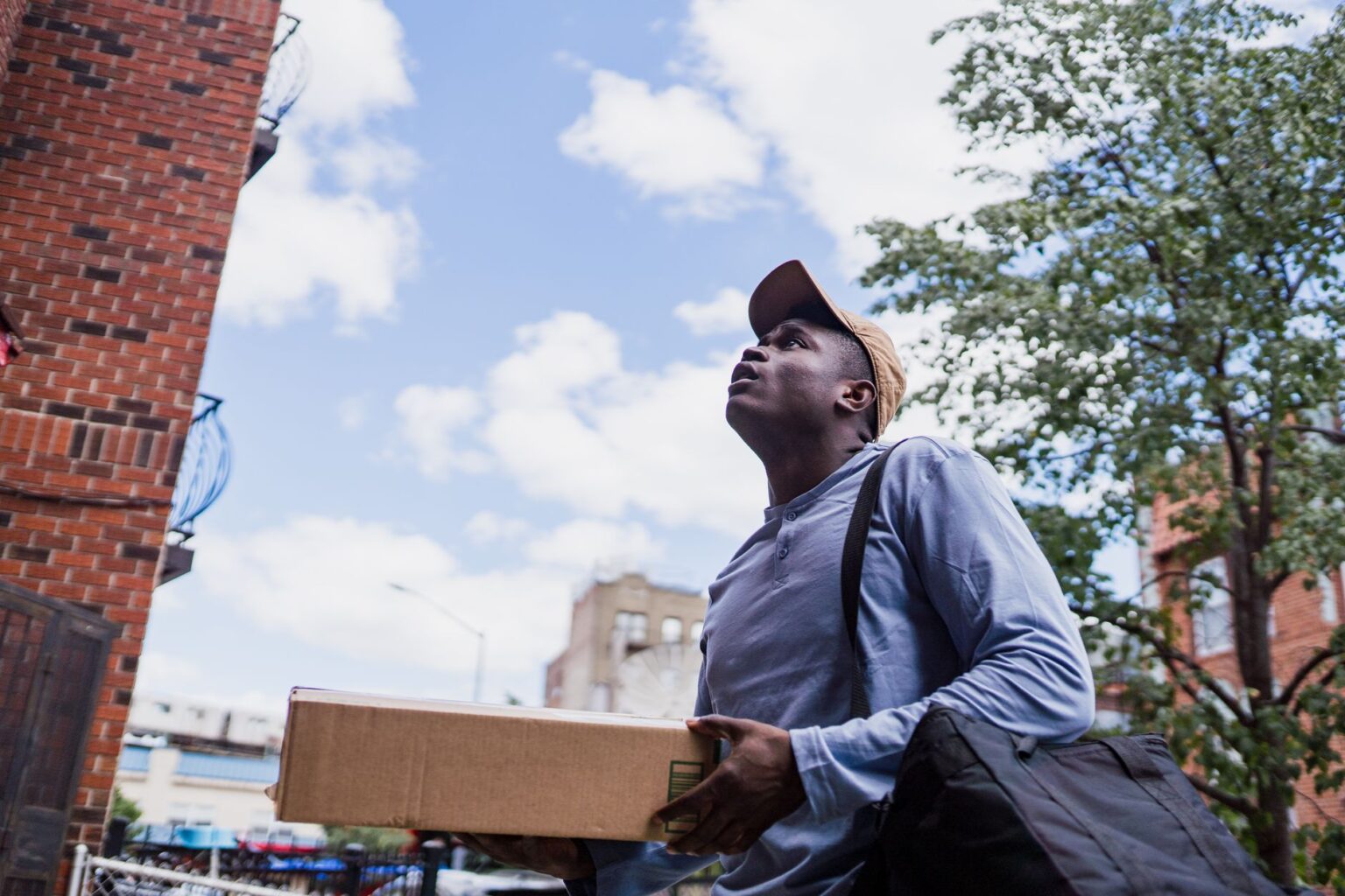 A gig economy delivery worker on a bicycle carrying a food delivery bag in an urban setting