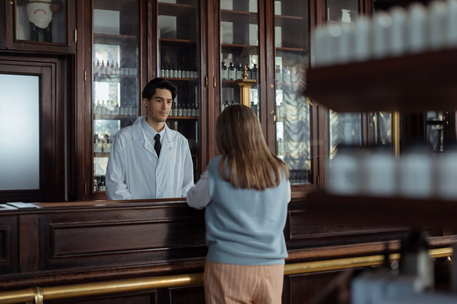 Pharmacist at a retail pharmacy counter reviewing prescription orders