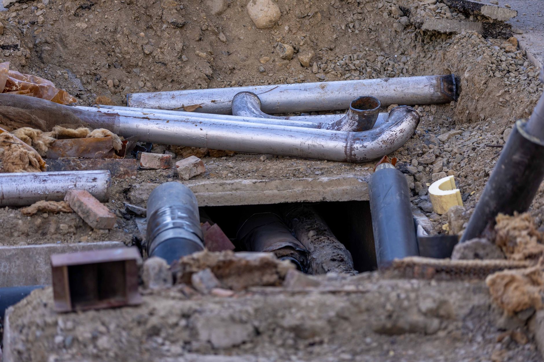 Aging underground water pipes showing wear and corrosion beneath a city street