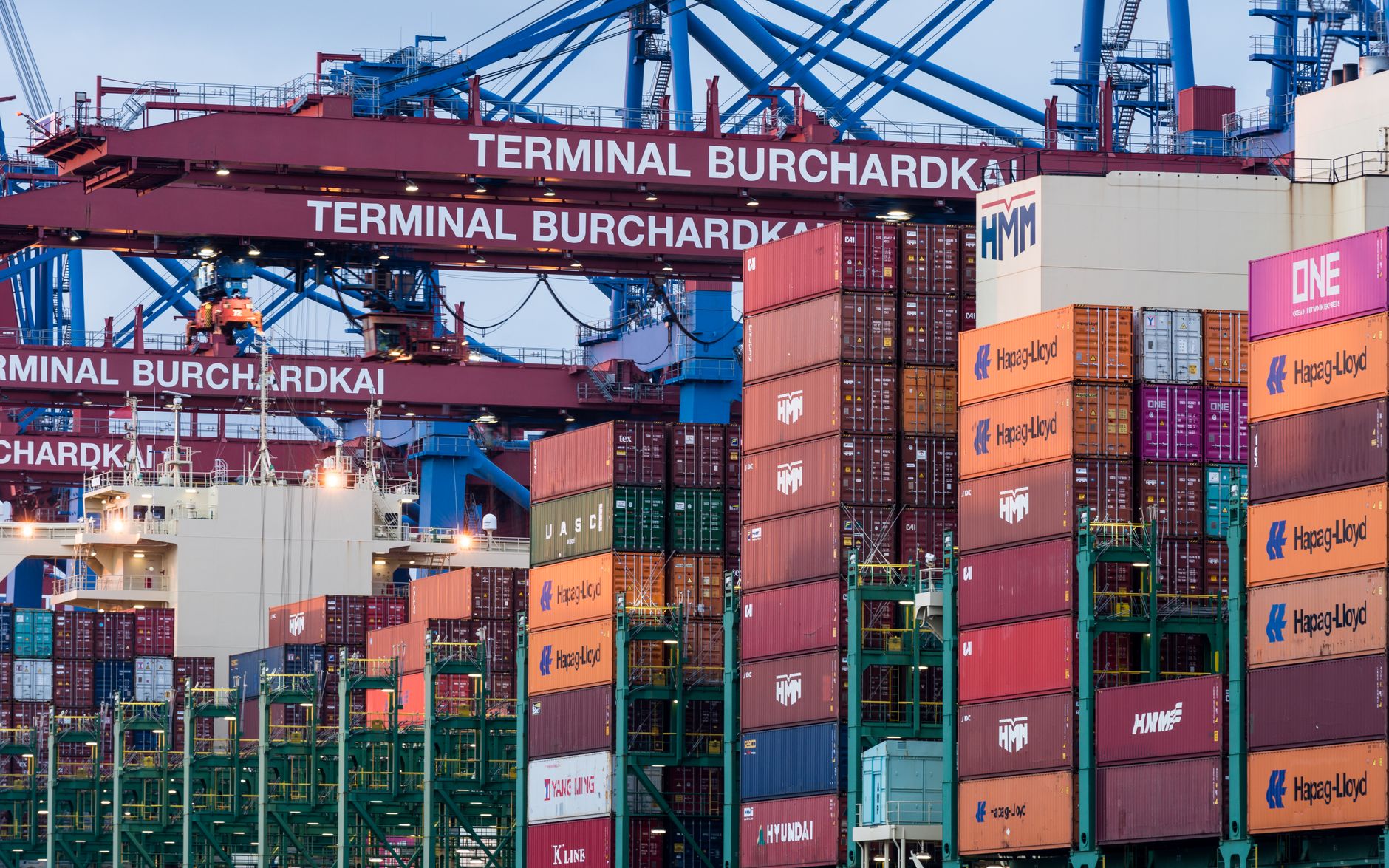 Shipping containers stacked at a busy commercial port terminal
