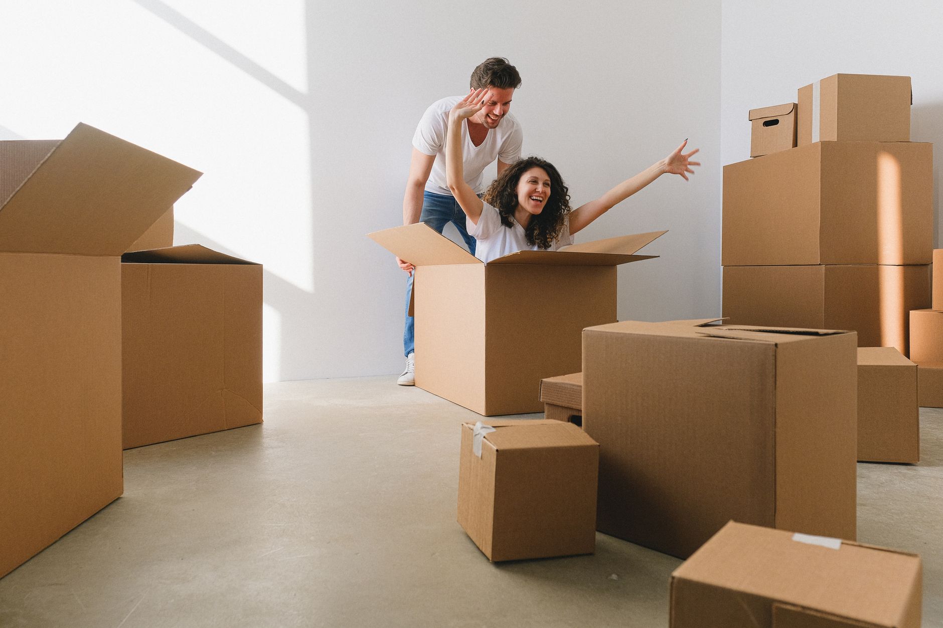 A young couple carrying moving boxes into a home representing first-time homebuyers navigating rent-to-own arrangements