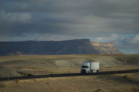 A long-haul semi truck driving along a wide American highway under open sky