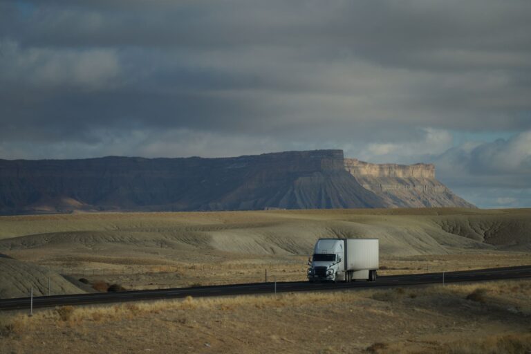 A long-haul semi truck driving along a wide American highway under open sky