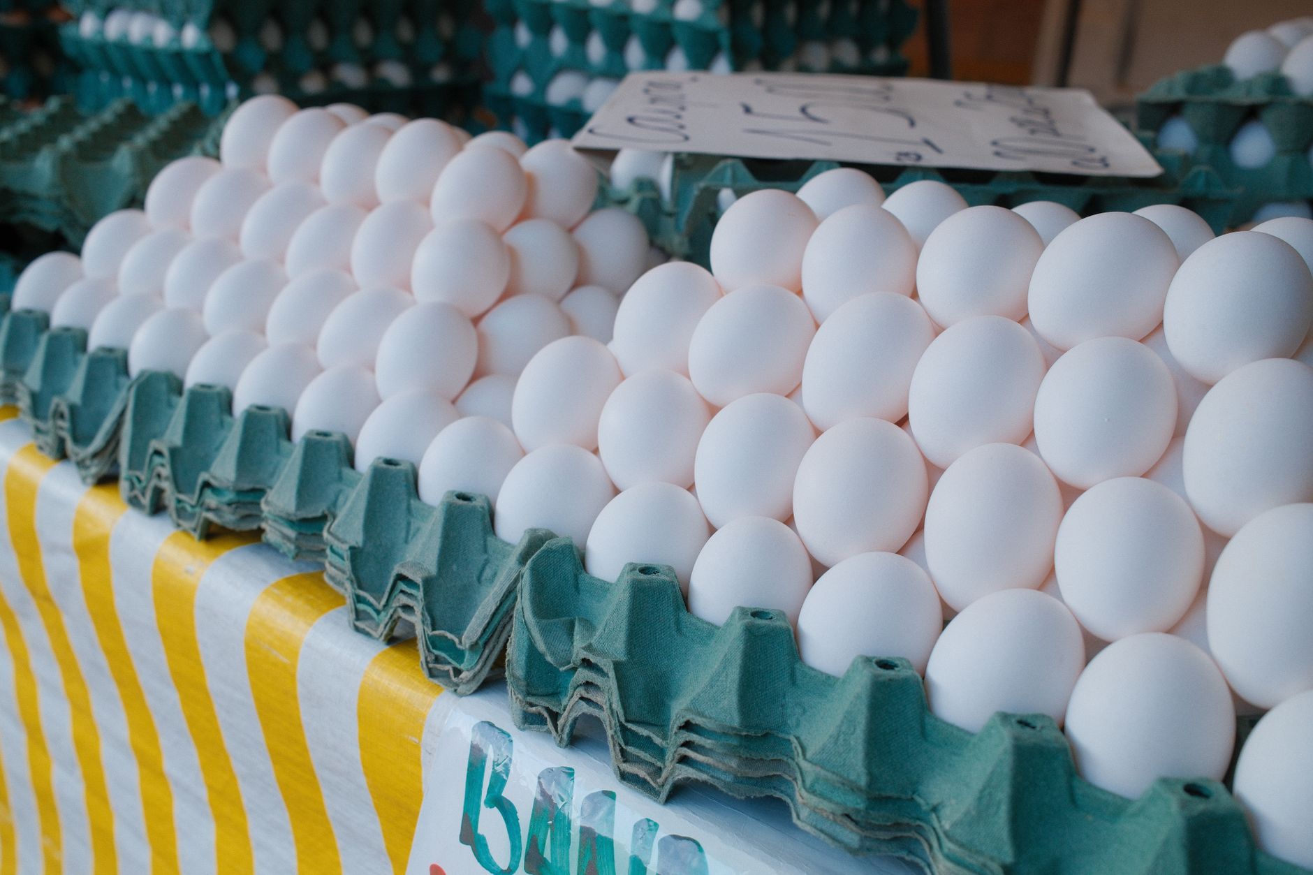 Cartons of fresh eggs stacked in a commercial grocery or food service setting