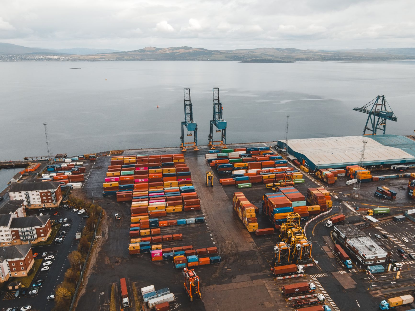 Large shipping containers stacked at a busy commercial seaport