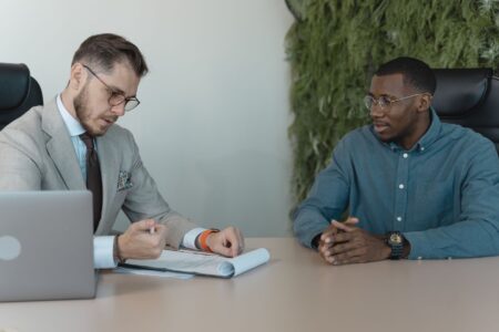 Visa Sponsorship Freezes Quietly Reshape High-Skill Hiring Markets Two professionals meeting across a desk during a job interview in a modern office setting