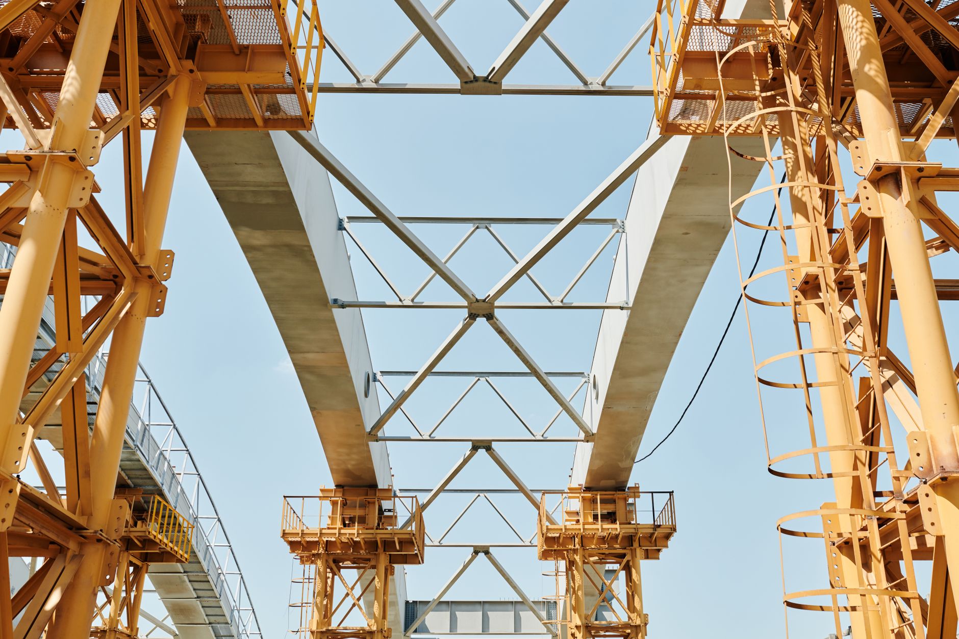 Large infrastructure construction site with cranes and steel framework against a clear sky