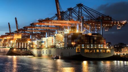 Freight Rate Whipsaws Leave Importers Scrambling for Contract Cover Large cargo ship docked at a busy commercial port with stacked shipping containers
