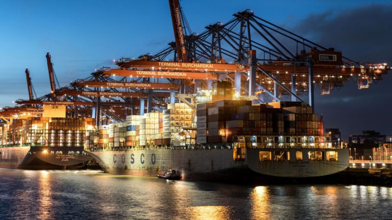 Freight Rate Whipsaws Leave Importers Scrambling for Contract Cover Large cargo ship docked at a busy commercial port with stacked shipping containers