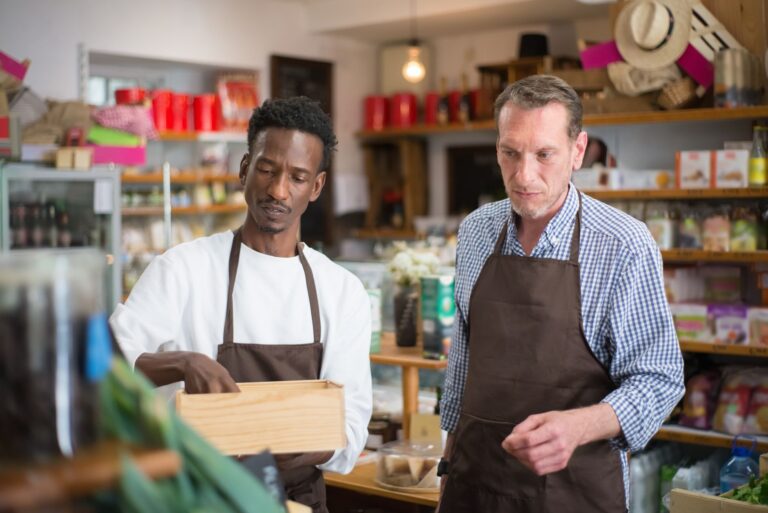 A small business owner looking stressed while reviewing financial documents at a shop counter