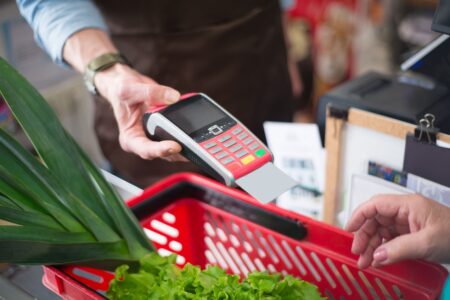 Customer scanning loyalty card at grocery store checkout counter