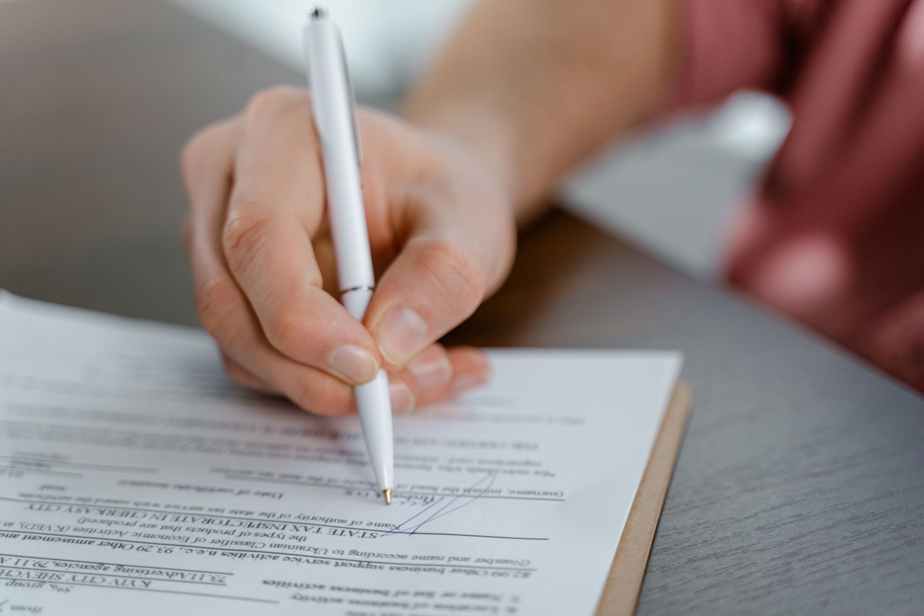 Person reviewing and signing a financial contract document at a desk