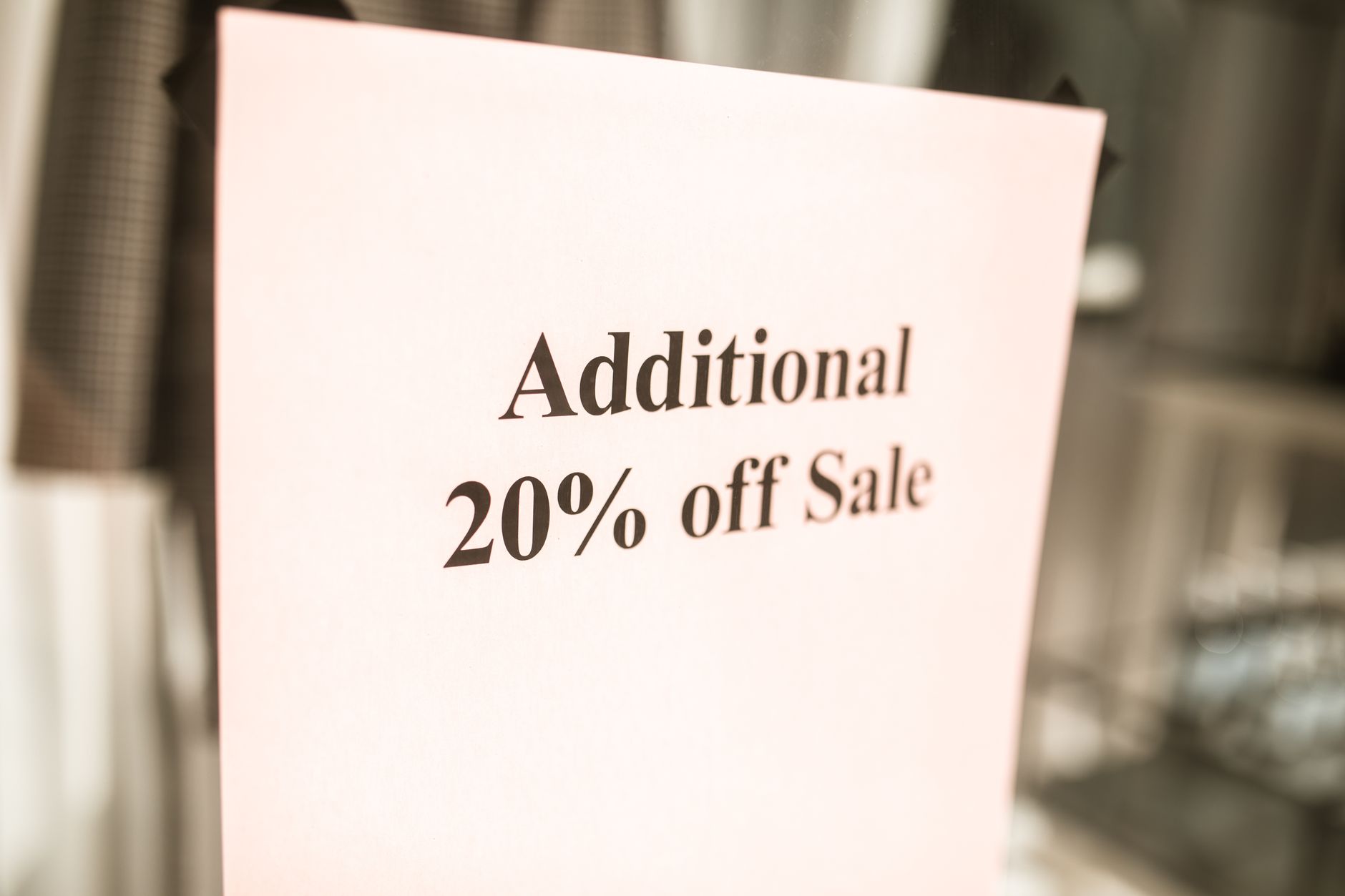 Retail store displaying multiple discount and sale signs in window