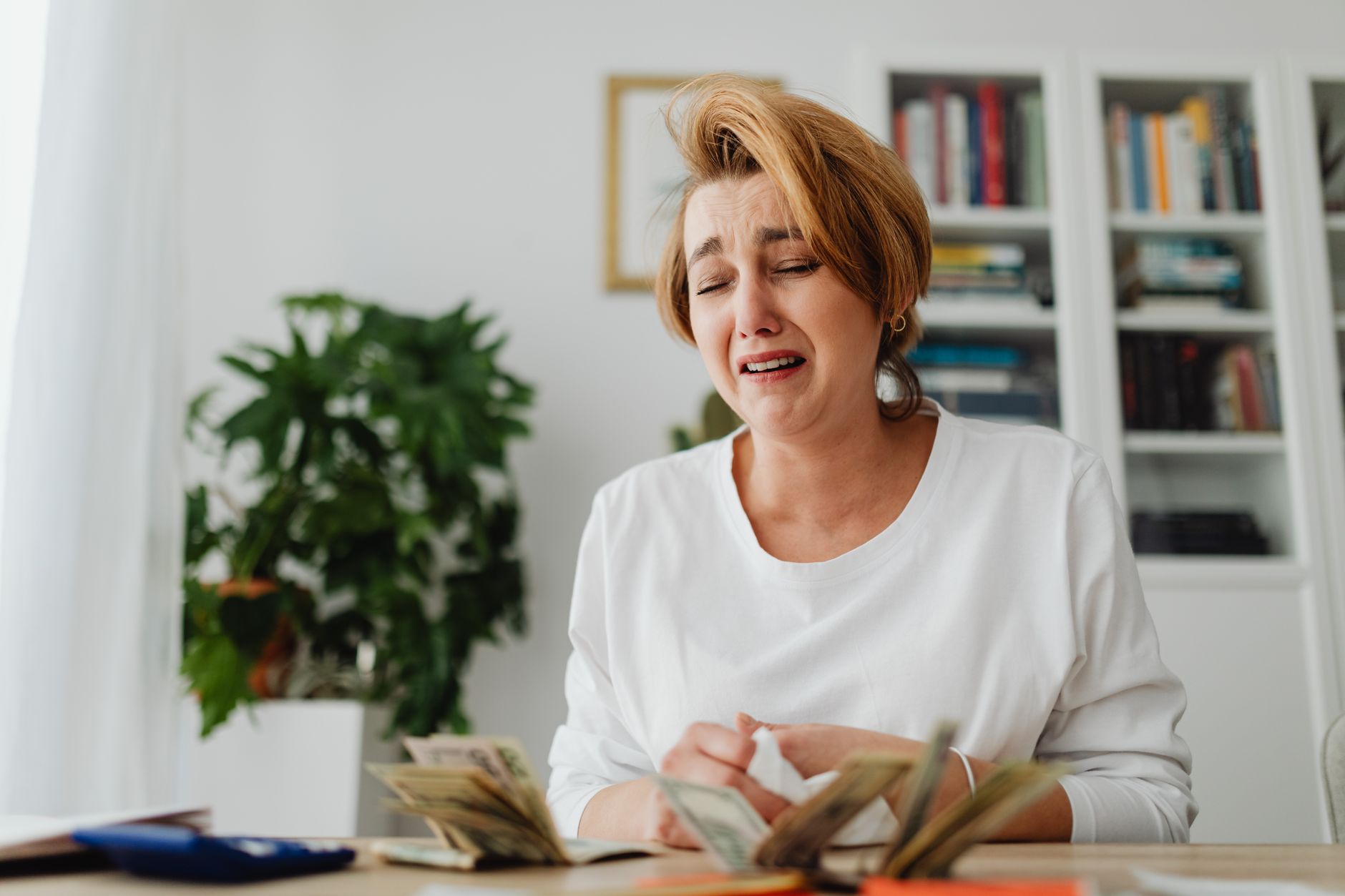 Person sitting at a table with documents and calculator looking stressed