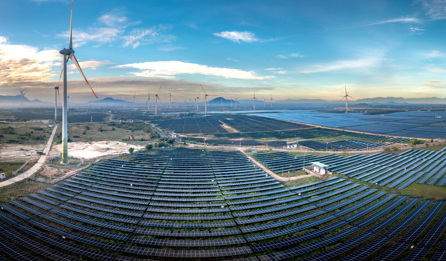 Aerial view of a large solar farm with rows of photovoltaic panels in an open field