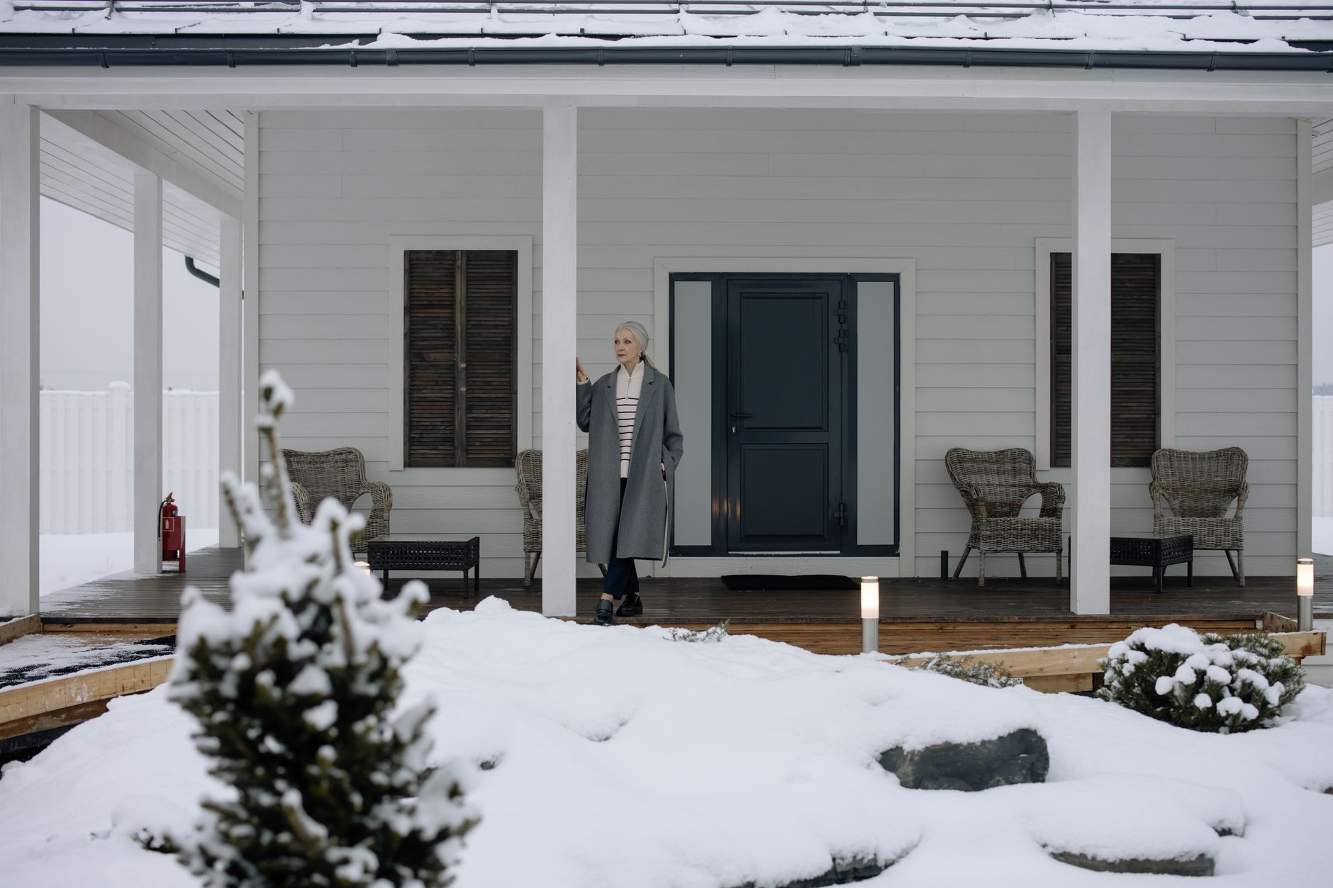 A suburban home in winter with snow on the ground and roof